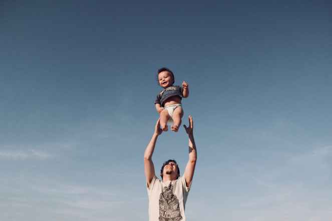 photo of man in raising baby under blue sky